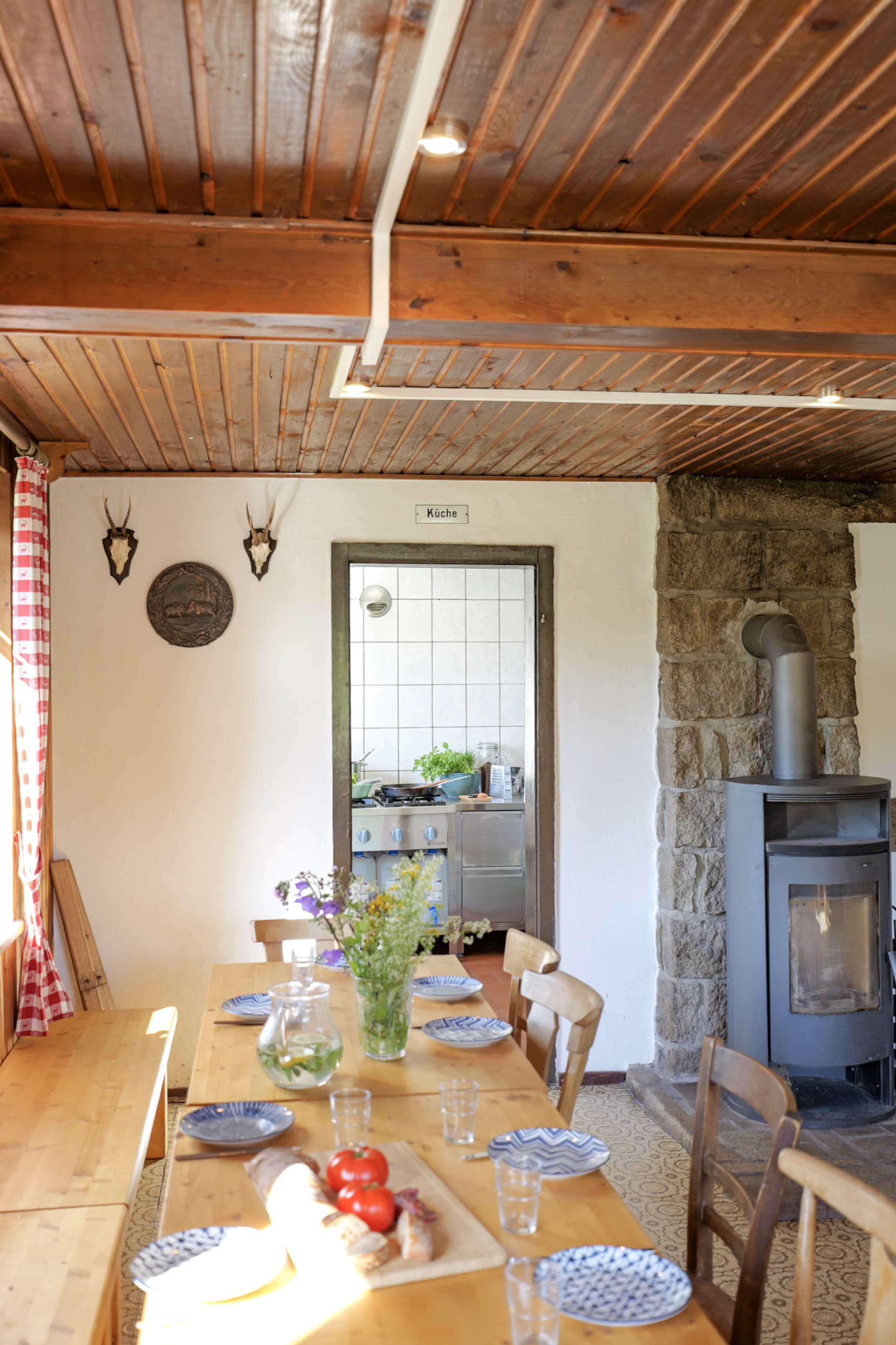bergwacht-esszimmer-gedeckter-tisch-mit-kaminofen-und-hirschgeweih