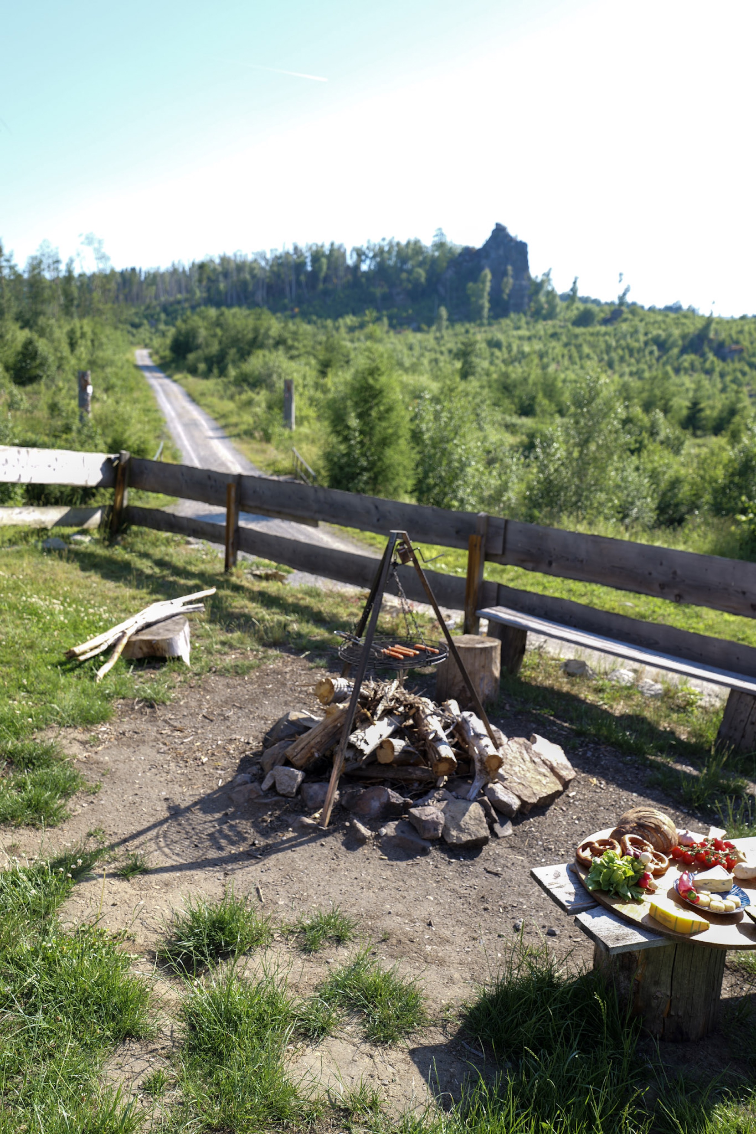 bergwacht-lagerfeuer-mit-wuerstchen-auf-dreibein-grill-und-blick-zum-fels