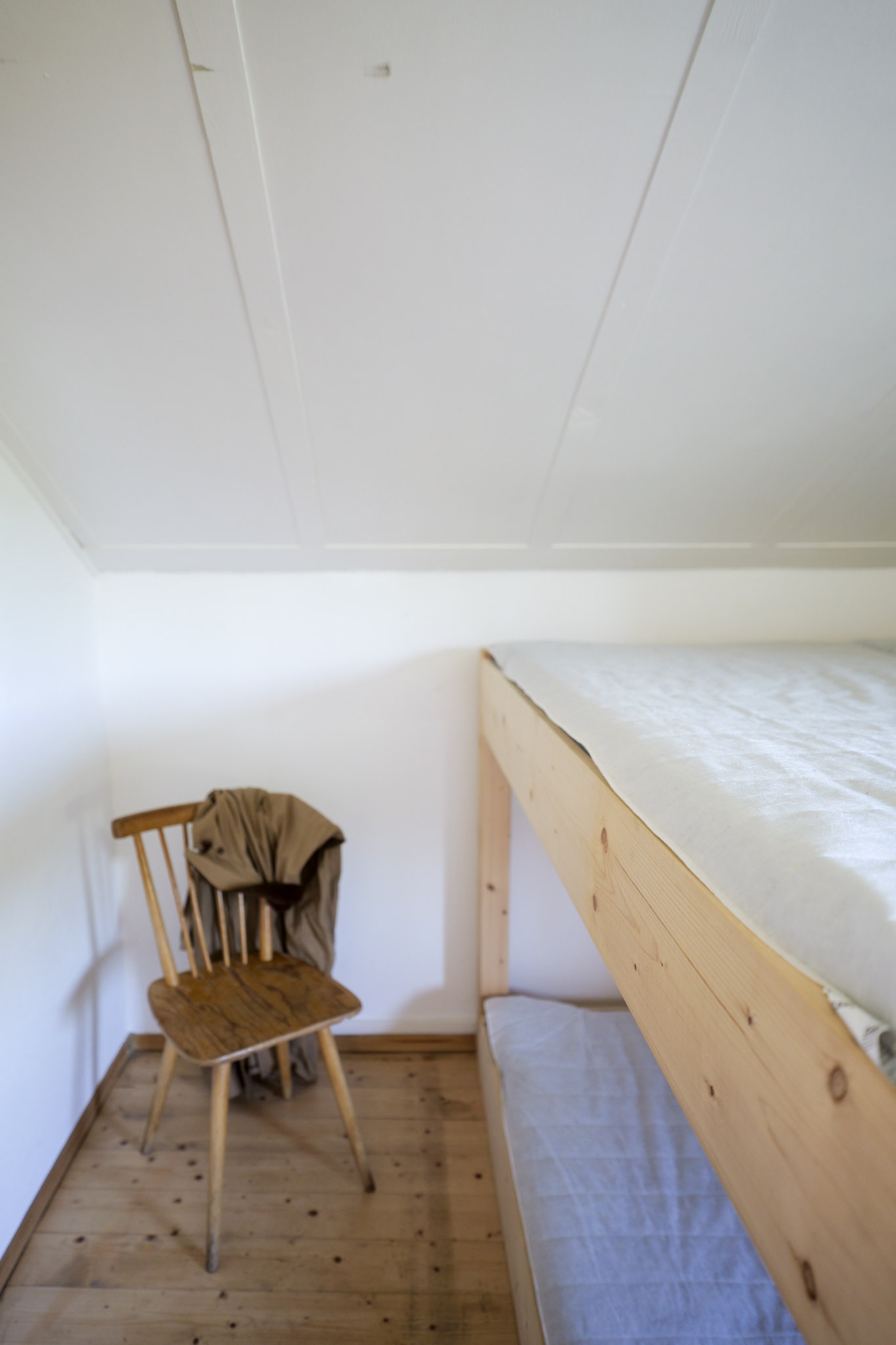 bergwacht-schlafsaal-ecke-mit-holzstuhl-und-jacke