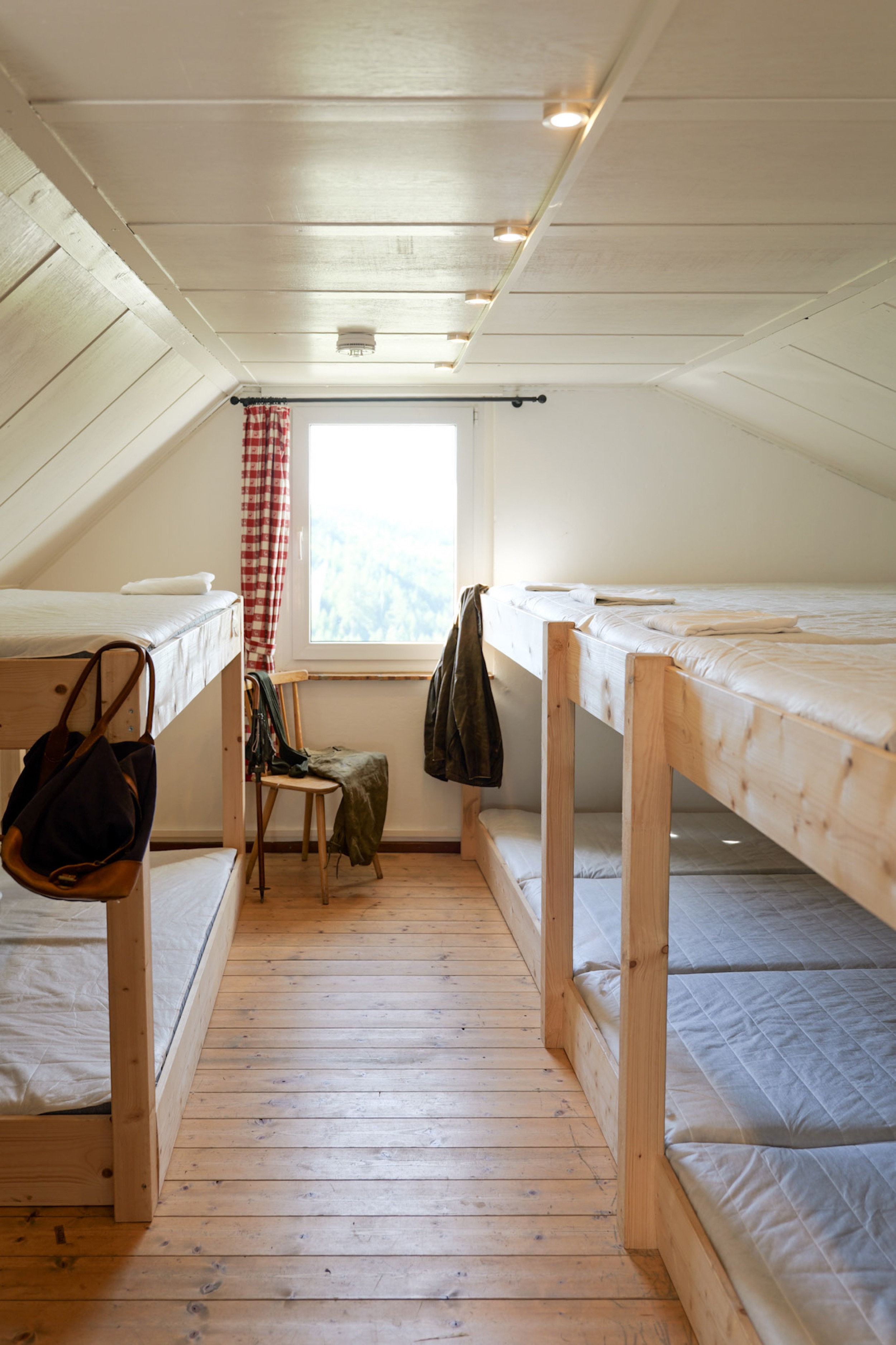 bergwacht-schlafsaal-stockbetten-blick-zum-fenster-mit-stuhl