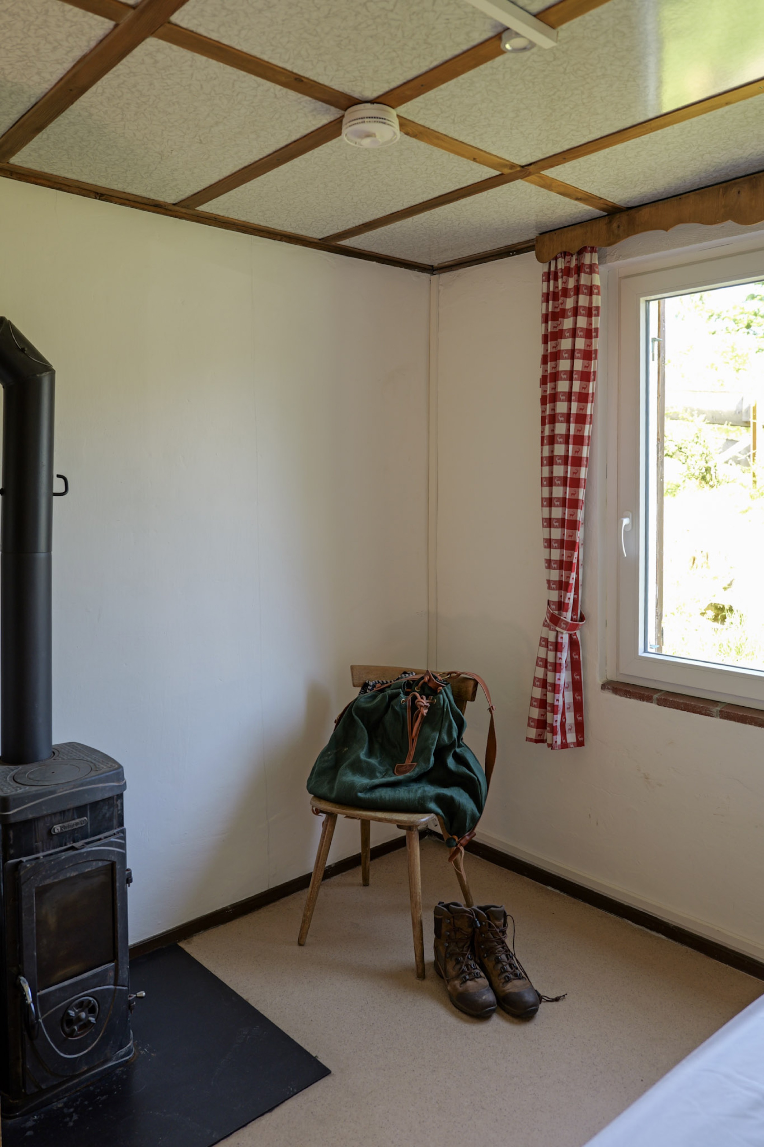 bergwacht-schlafzimmer-ecke-mit-ofen-rucksack-und-wanderschuhen