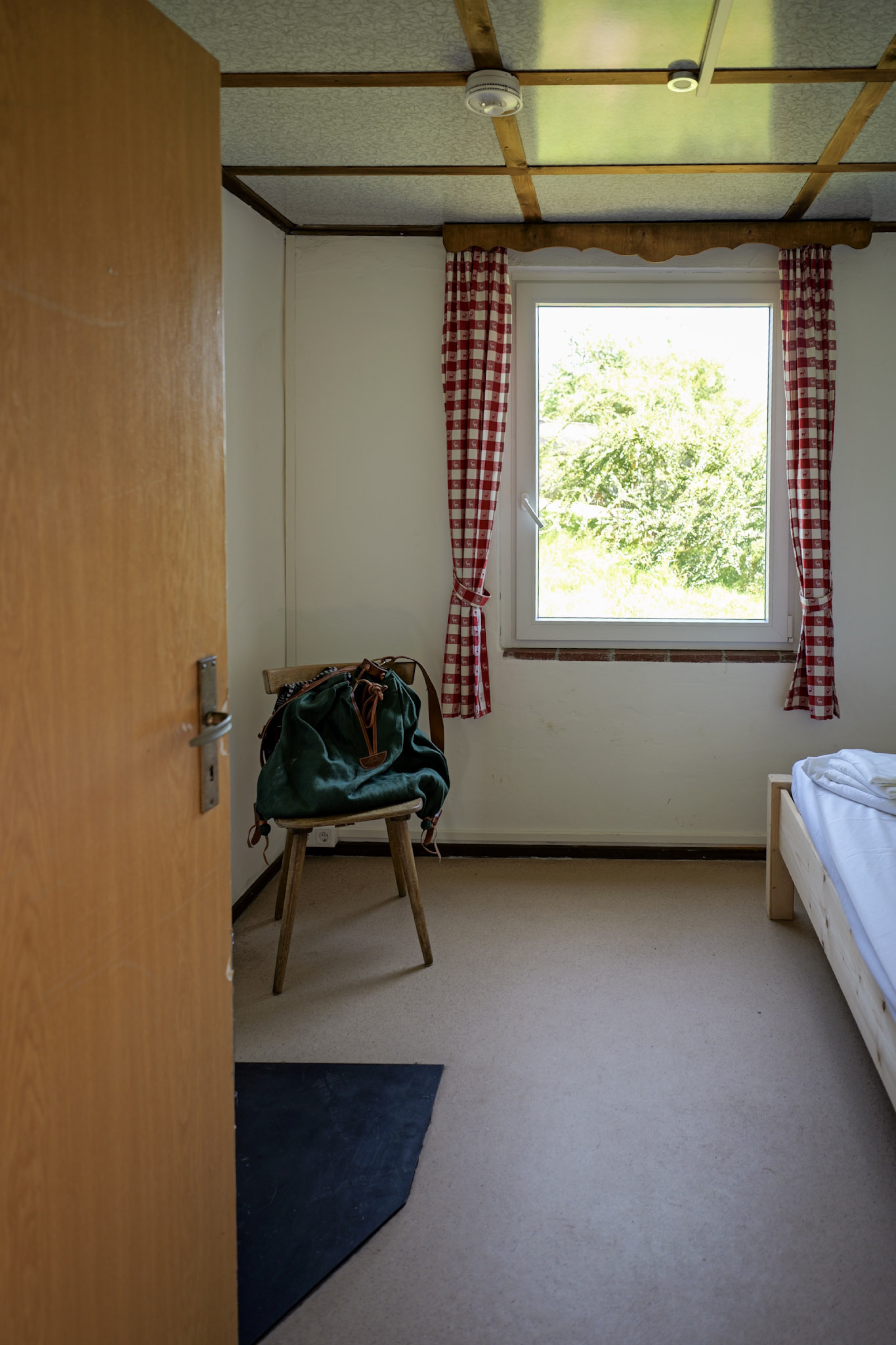 bergwacht-schlafzimmer-mit-holzbett-und-karierten-vorhaengen