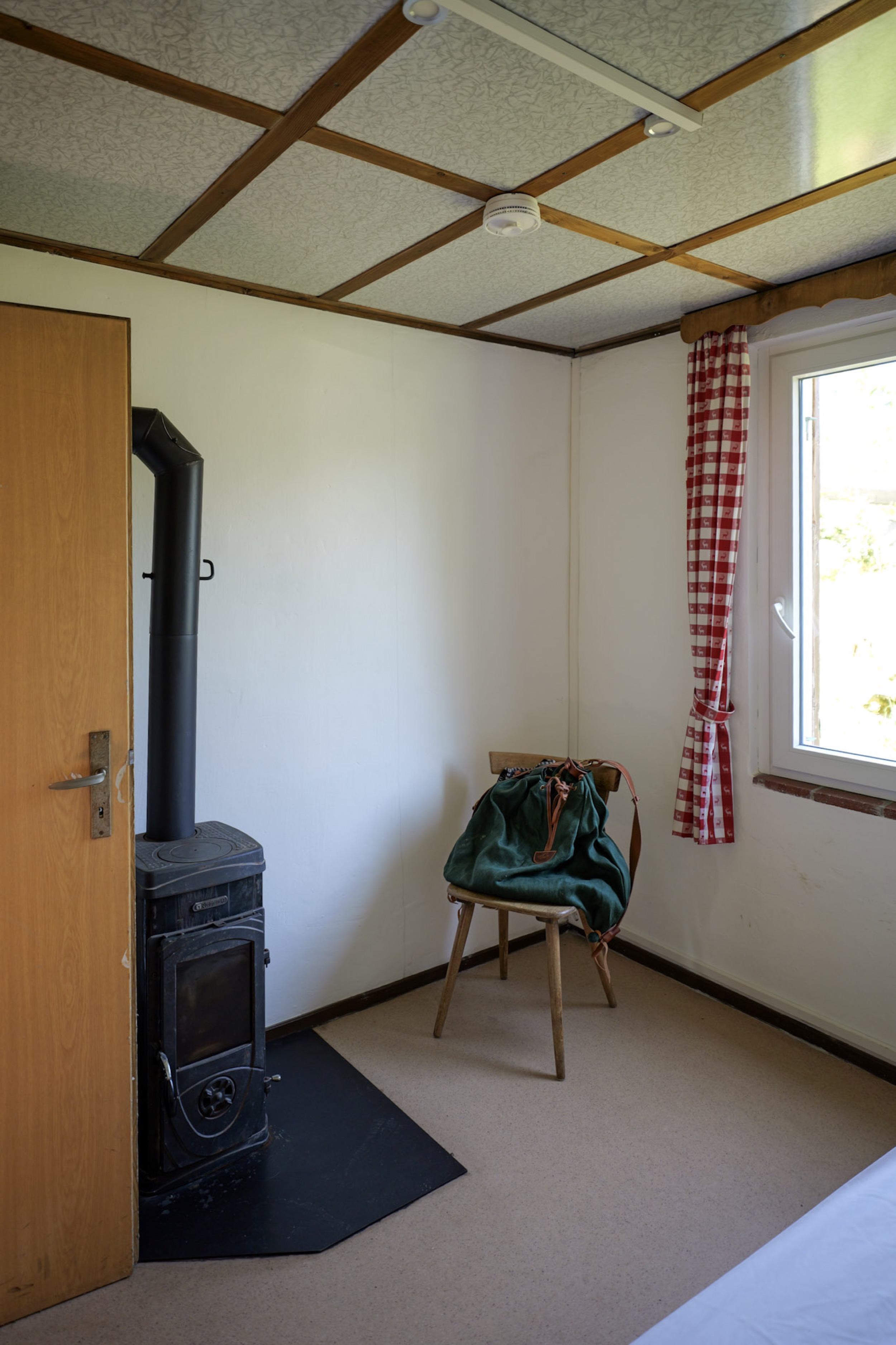 bergwacht-schlafzimmer-mit-holzofen-und-ofenrohr
