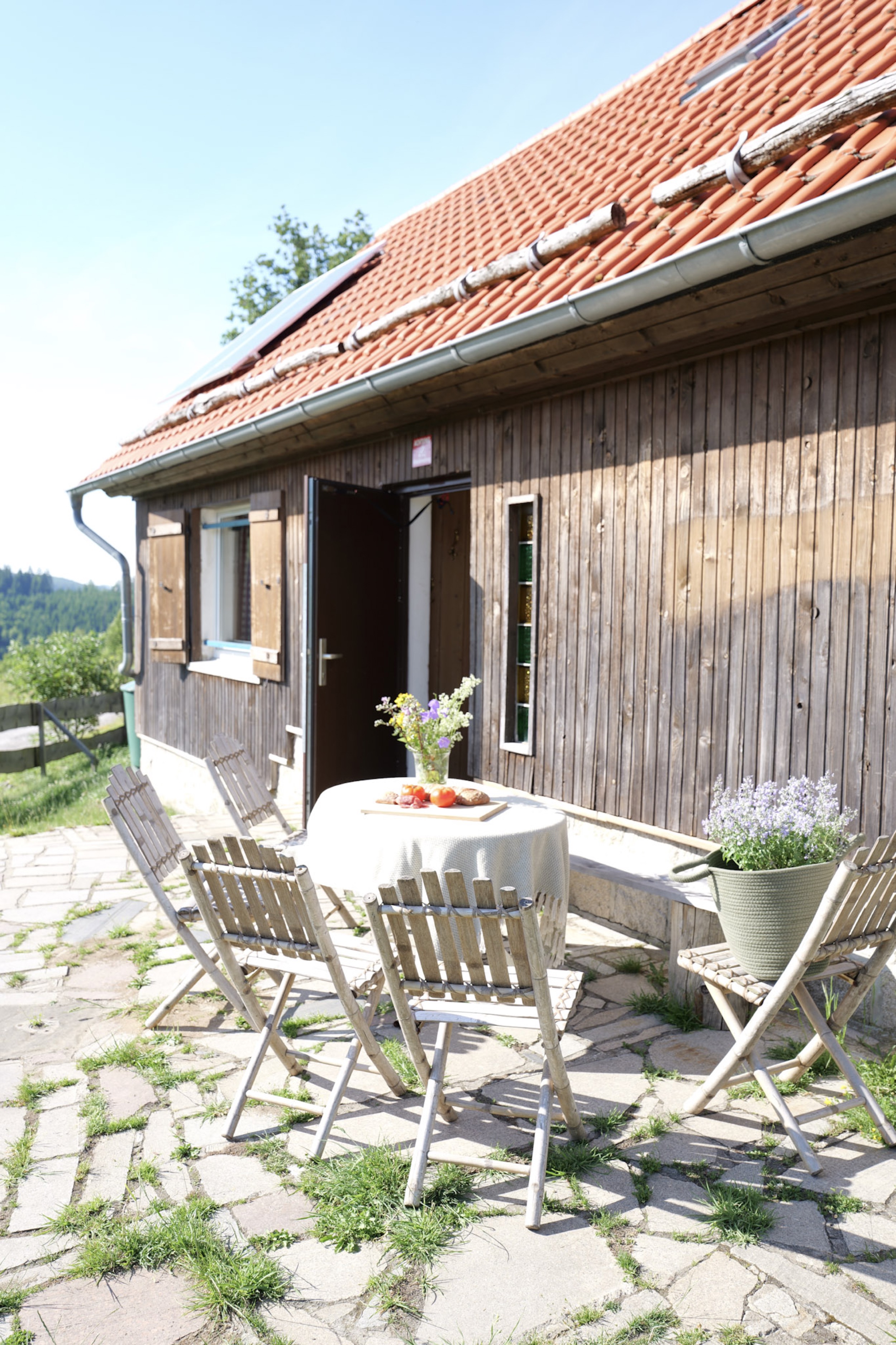 bergwacht-terrasse-holzhaus-mit-gartenmoebeln-und-blick-auf-huegel