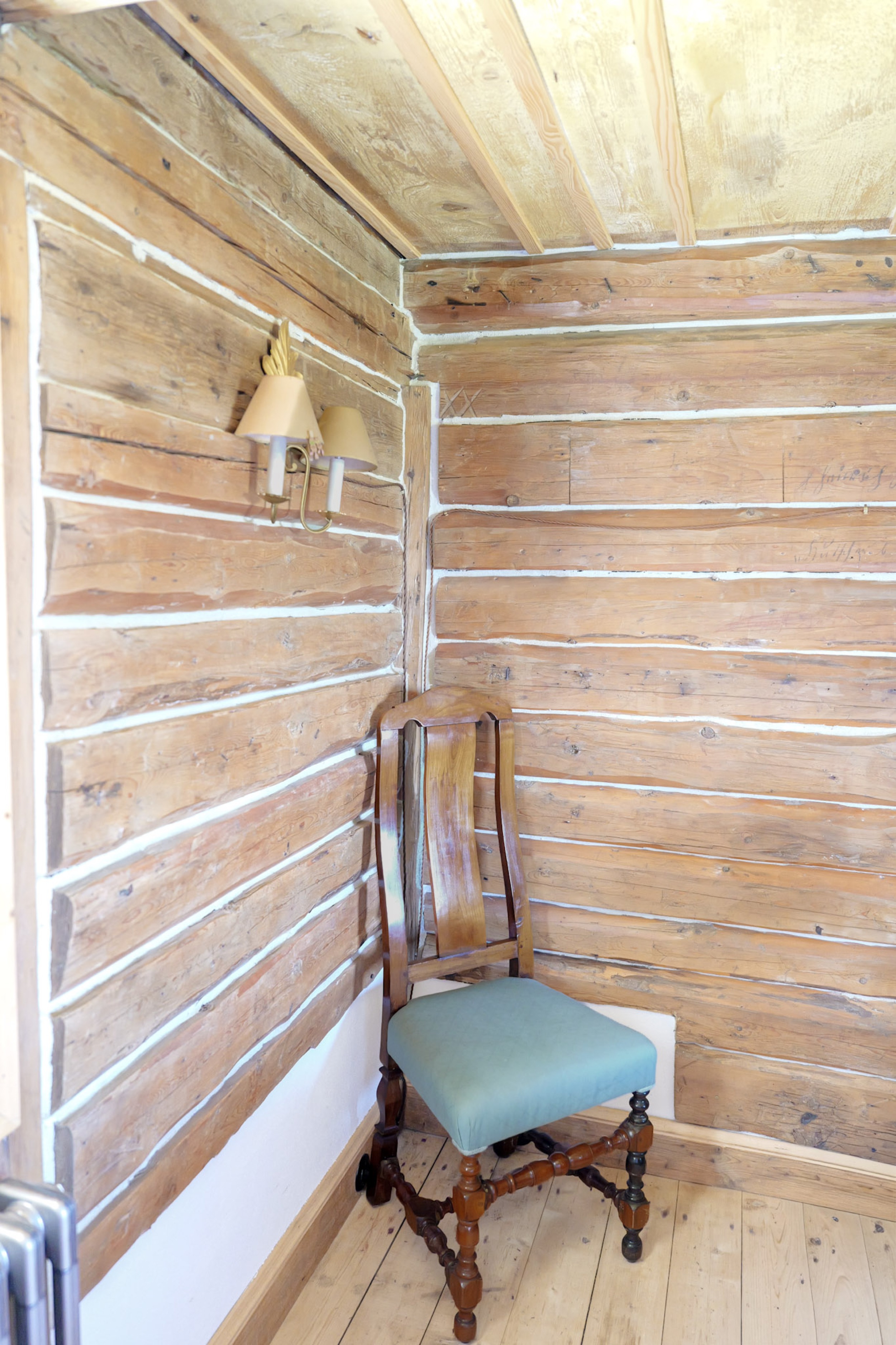 carlshaus-ecke-blockwand-wandleuchte-antiker-stuhl-gruener-sitz