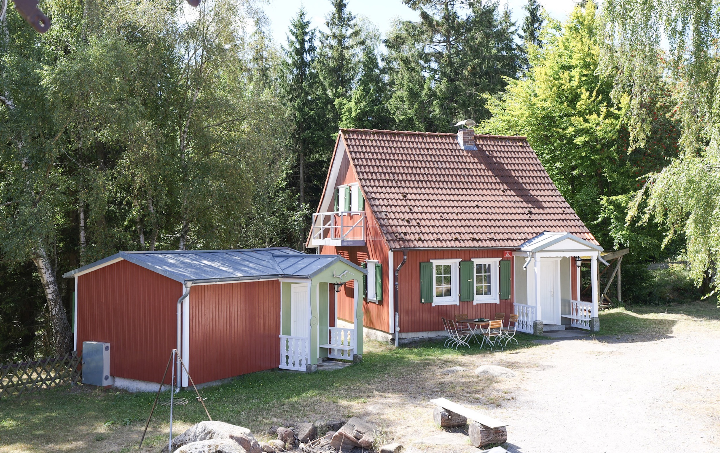 carlshaus holzhaus mit gruenen fensterlaeden und sitzterrasse zwischen birken