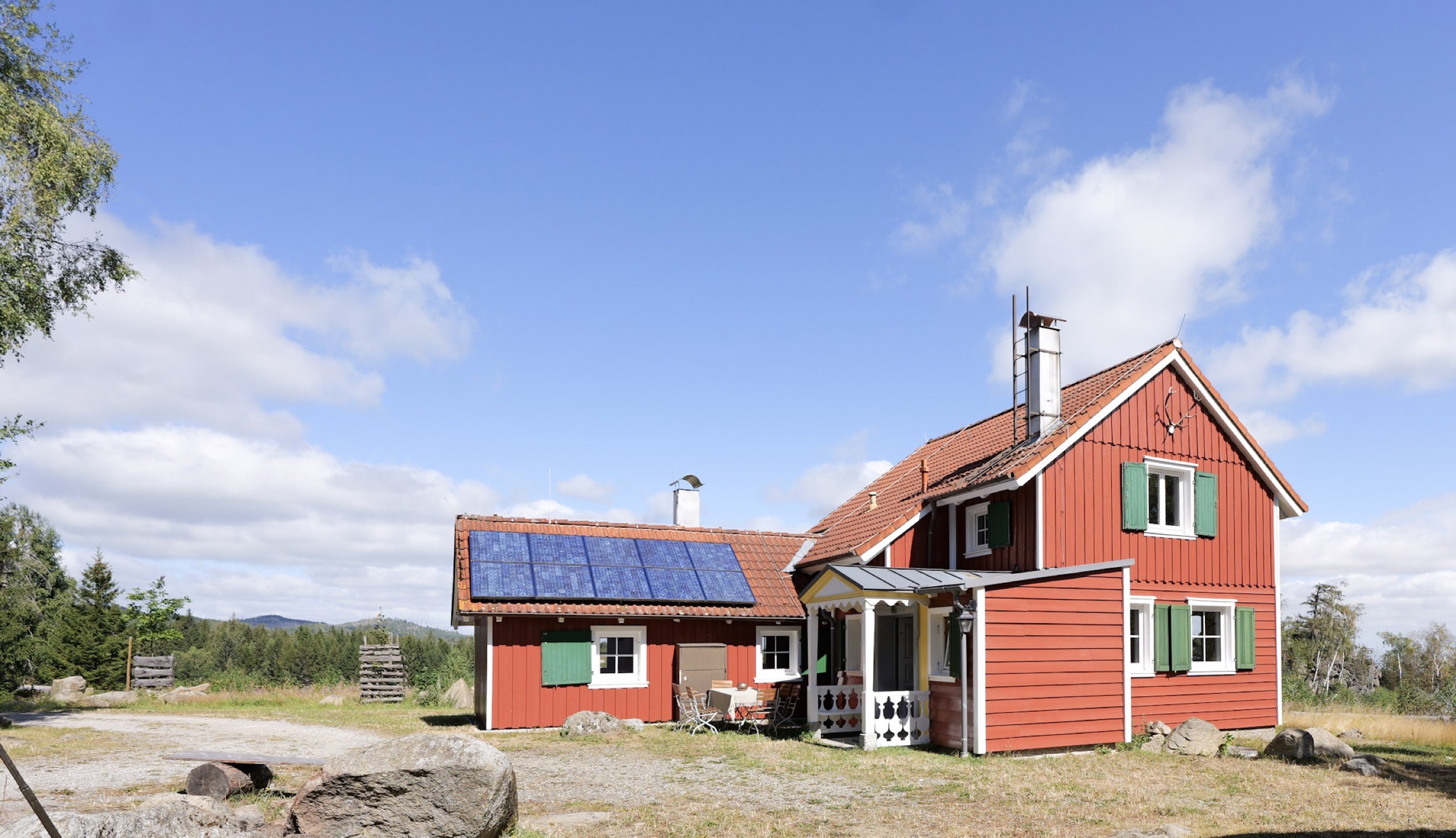 carlshaus seitenansicht mit solaranlage auf dem dach und huegeln im hintergrund