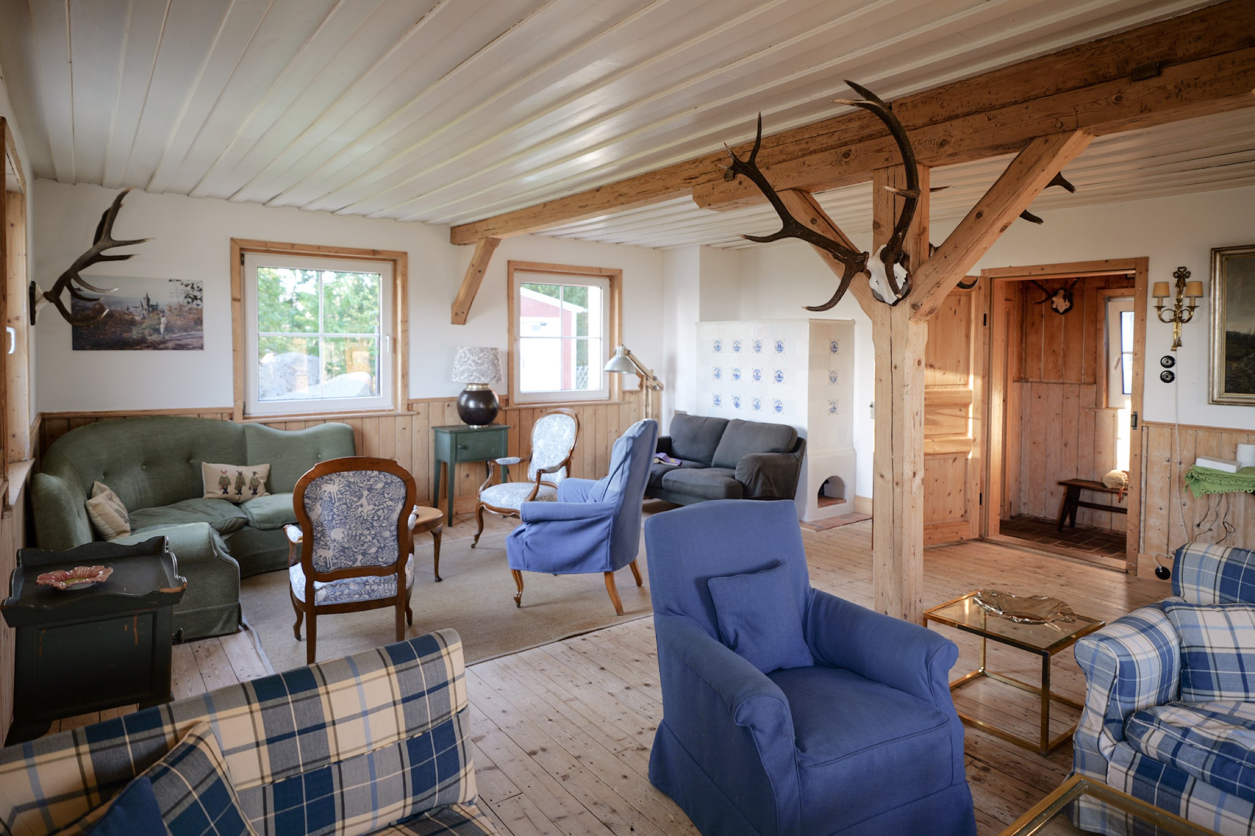 carlshaus wohnzimmer gruenes sofa geweihstuetze kachelofen durchgang flur