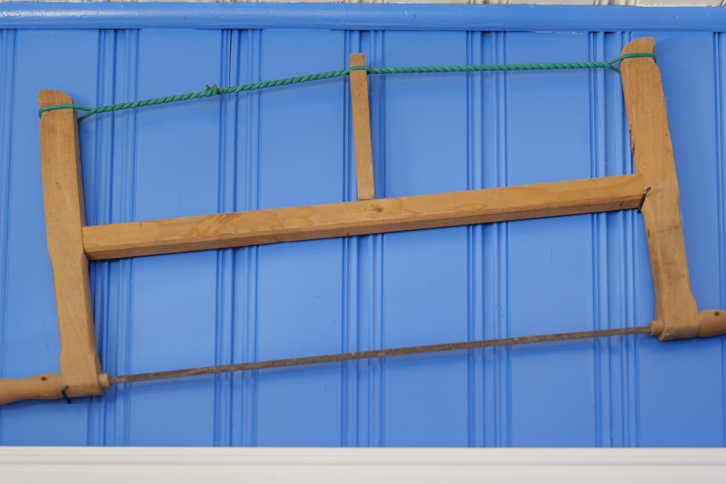 hexenhaus alte holzsaege als wanddekoration an blauer wand