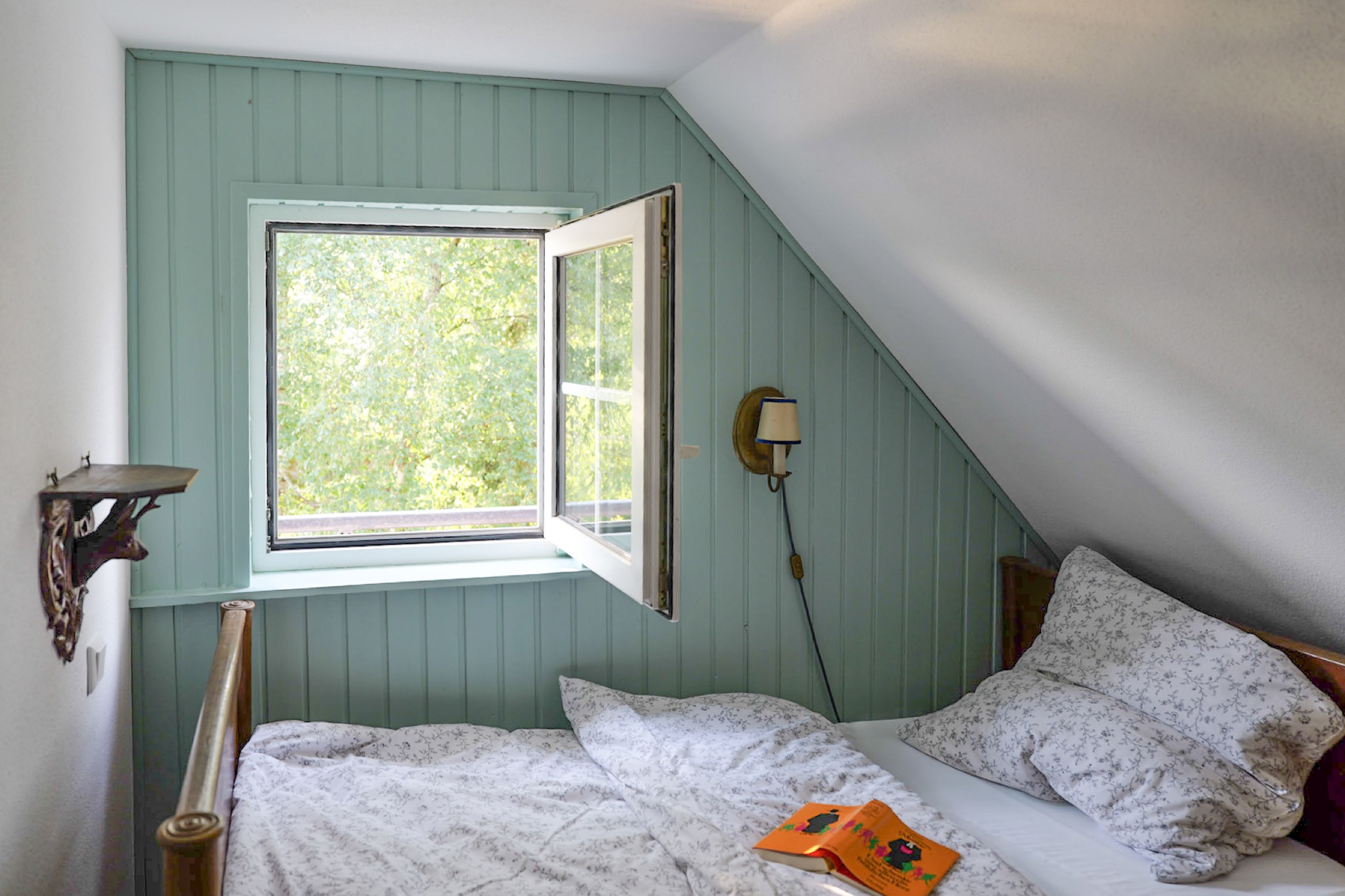 hexenhaus bett unter der dachschraege am offenen fenster nahaufnahme mit bilderbuch