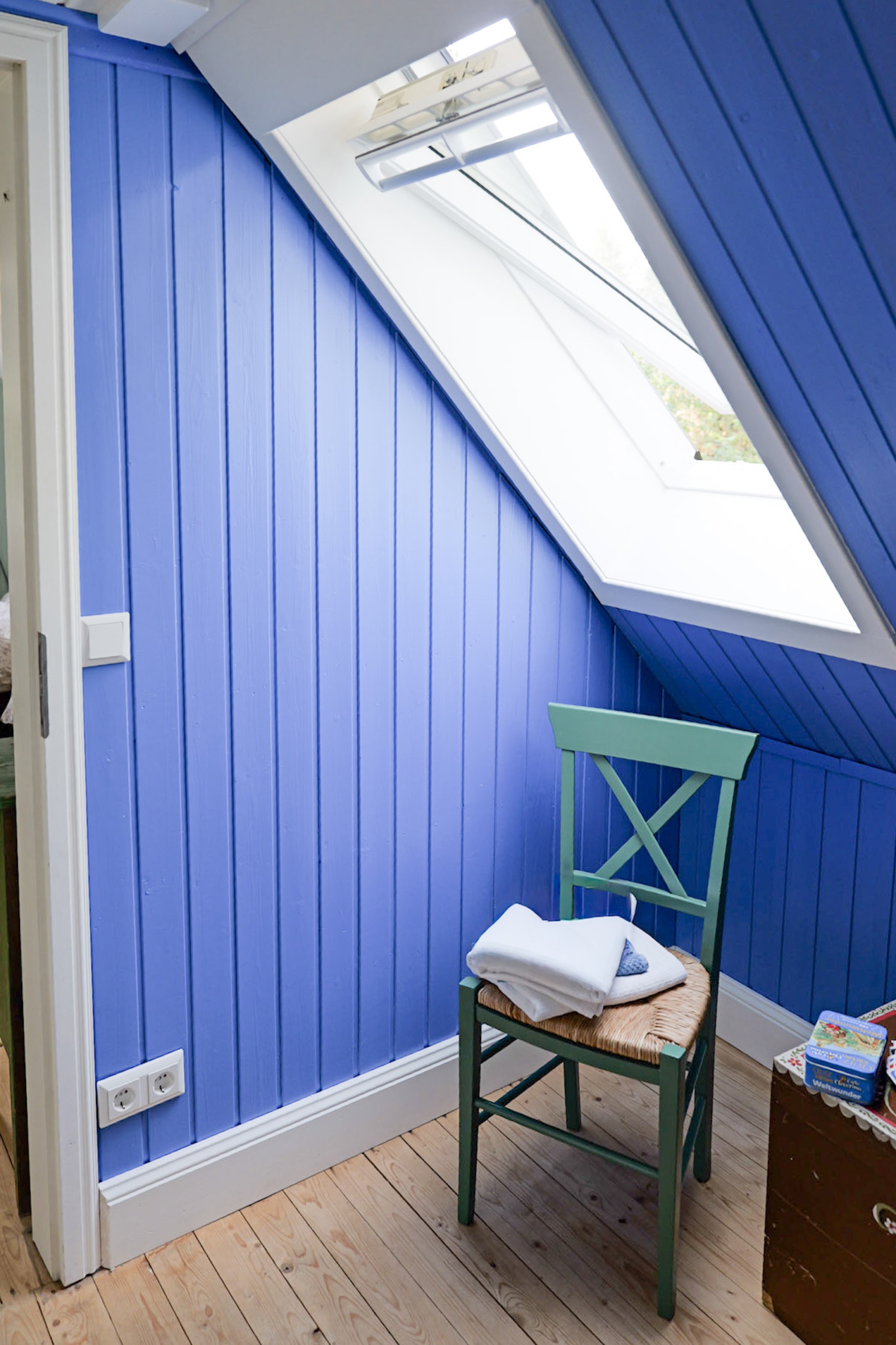 hexenhaus-blauer-alkoven-mit-dachfenster-gruenem-stuhl-und-handtuechern