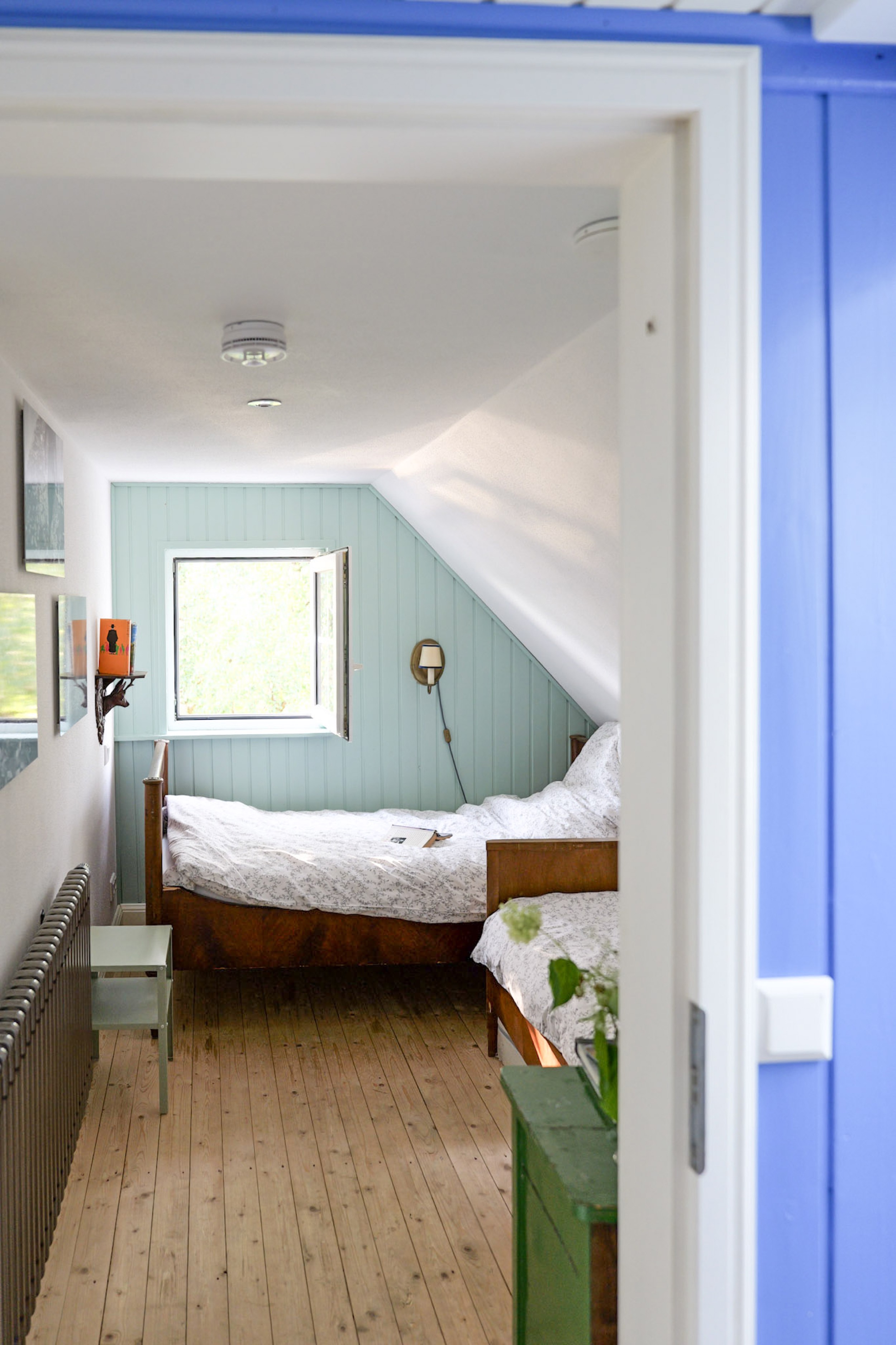 hexenhaus-blick-vom-blauen-zimmer-durch-die-tuer-ins-schlafzimmer-mit-blumenvase