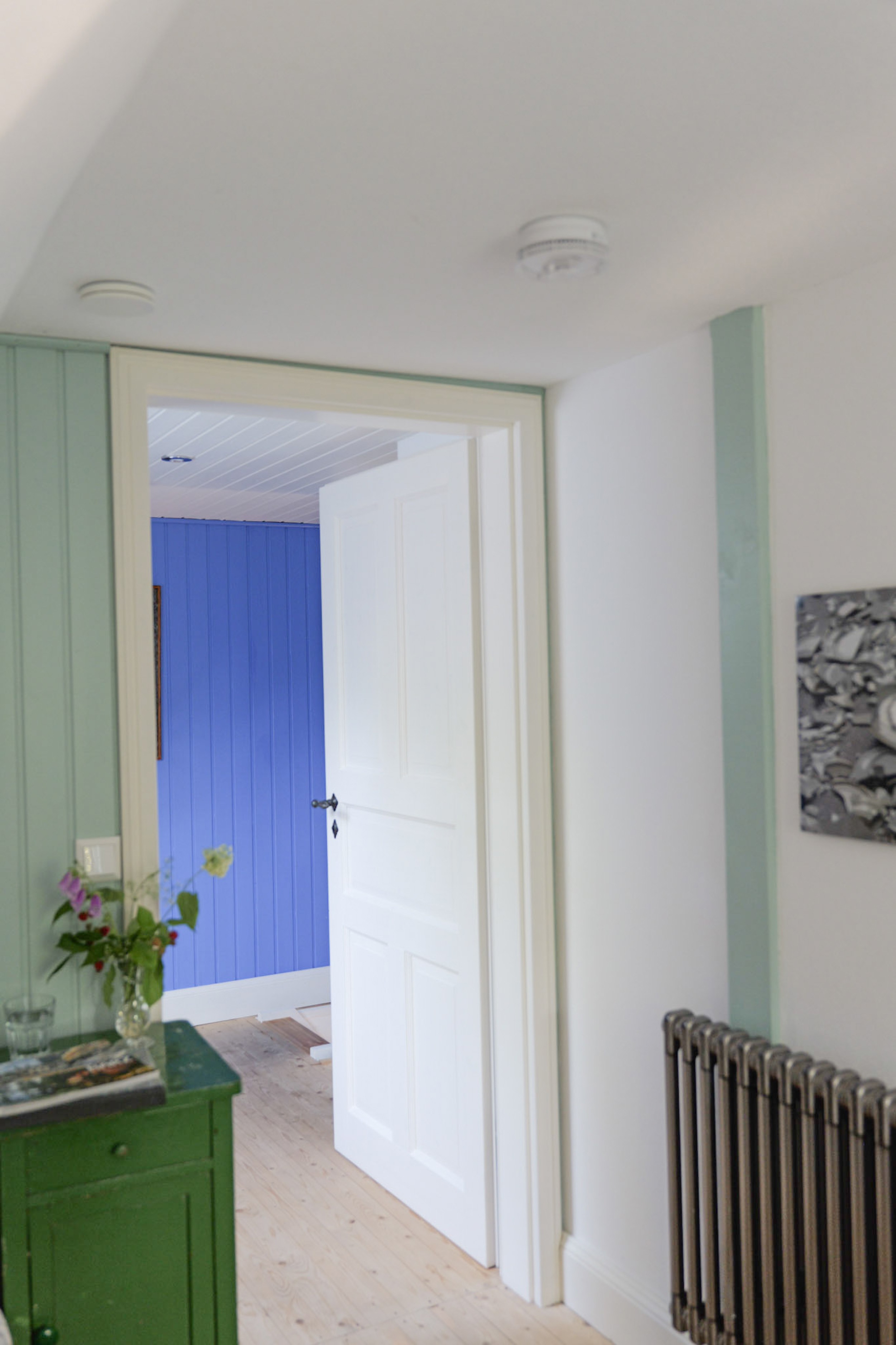 hexenhaus-flur-mit-gruener-kommode-blumenstrauss-und-blick-ins-blaue-zimmer