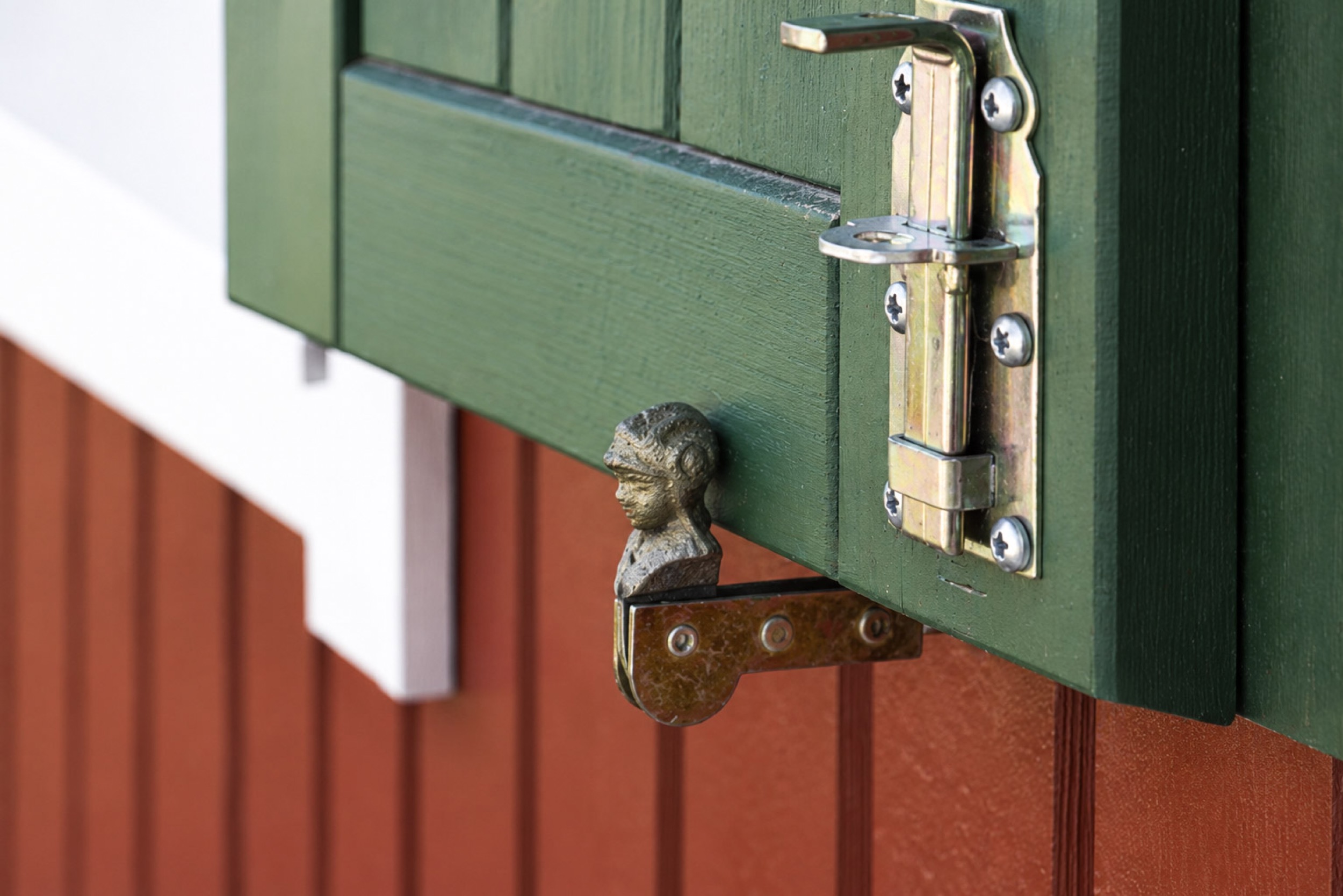 hexenhaus gruener fensterladen mit beschlag an roter fassade