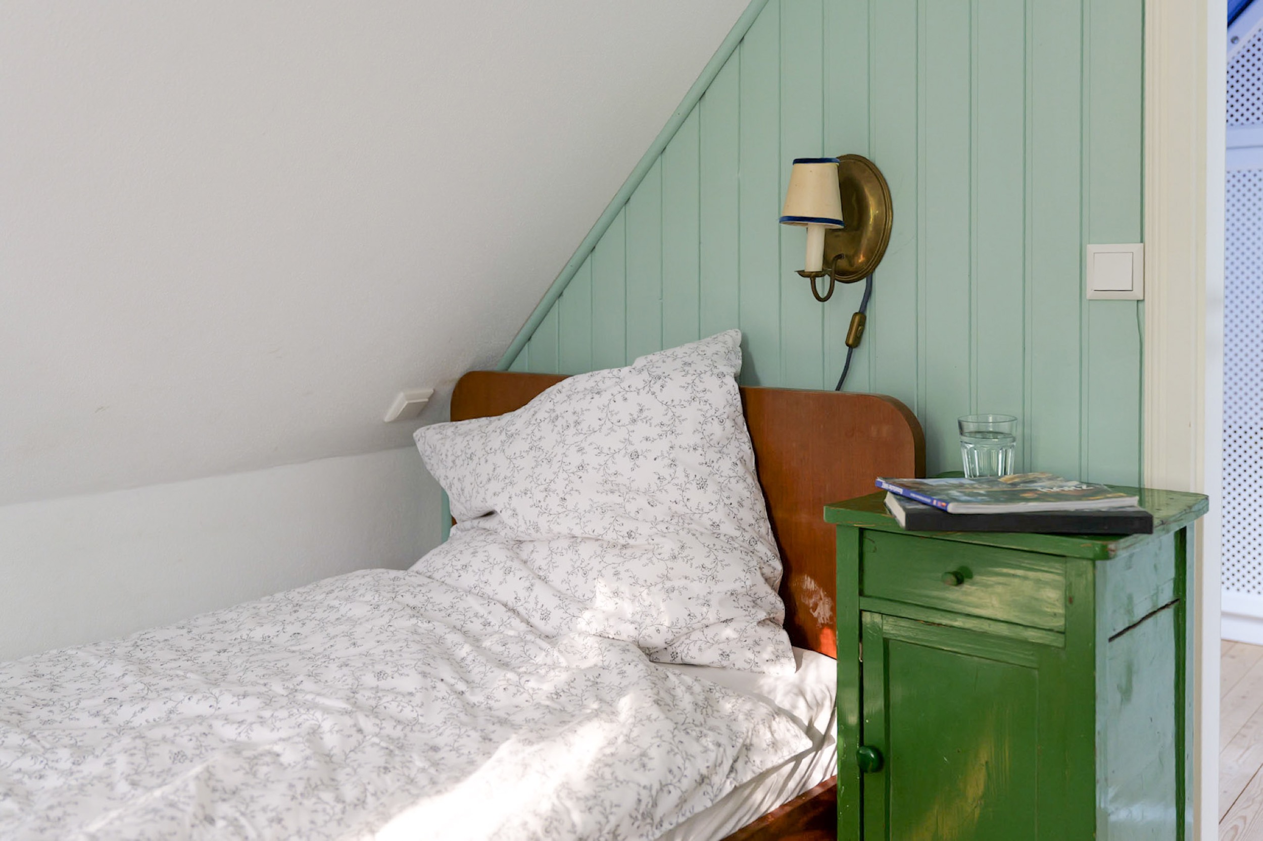 hexenhaus nachttisch mit buch und wasserglas im gruenen schlafzimmer
