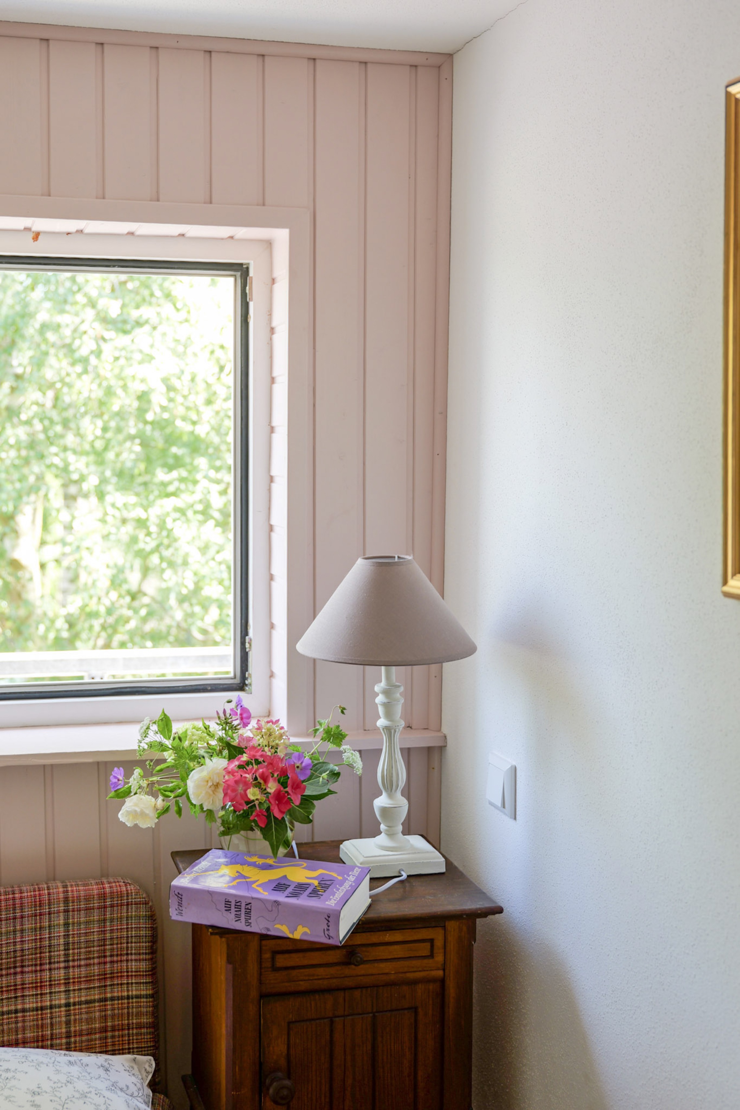 hexenhaus-nachttisch-mit-lampe-blumenstrauss-und-buch-am-fenster