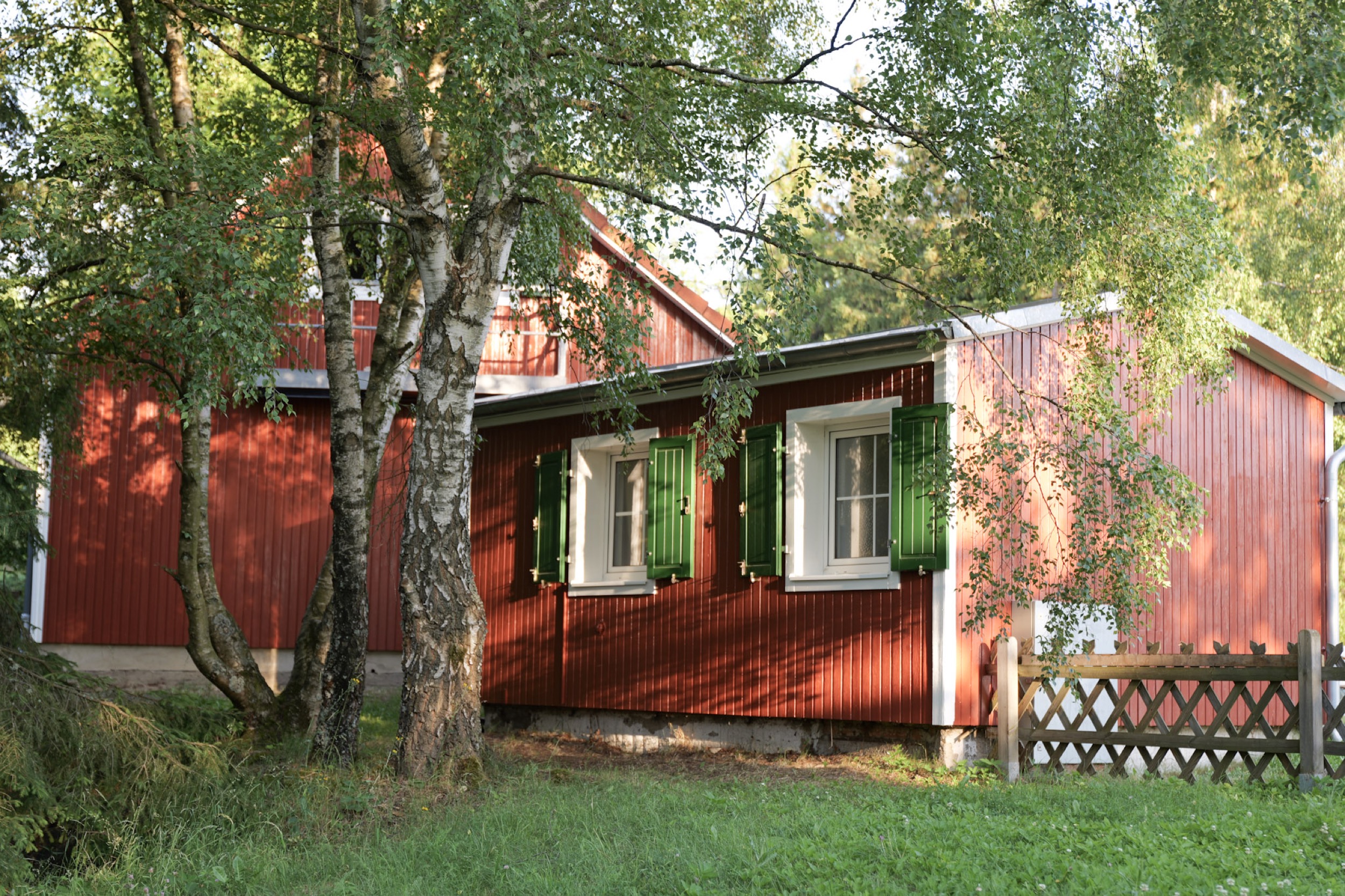 puppenhaus rotes haus mit gruenen fensterlaeden und lattenzaun